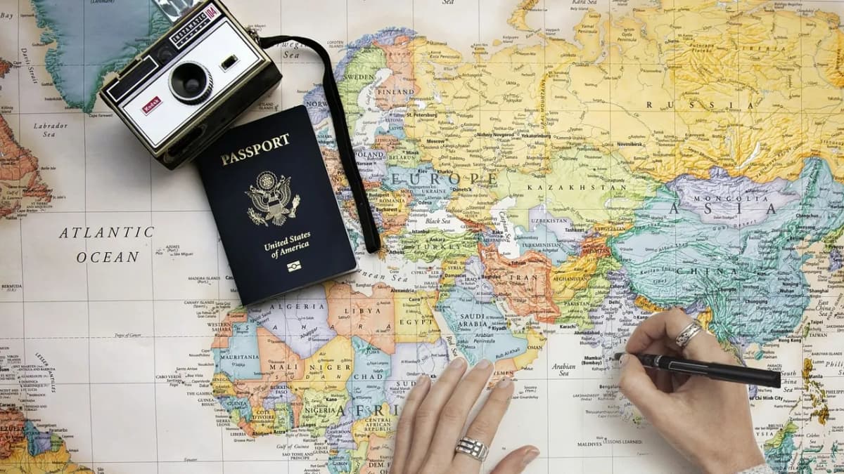Vintage camera and passport on a world map with a hand writing travel notes