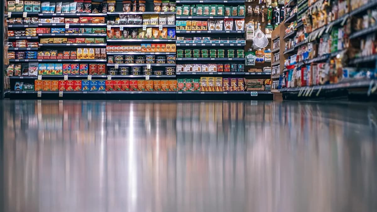 Supermarket aisle with fully stocked shelves reflected in a polished floor