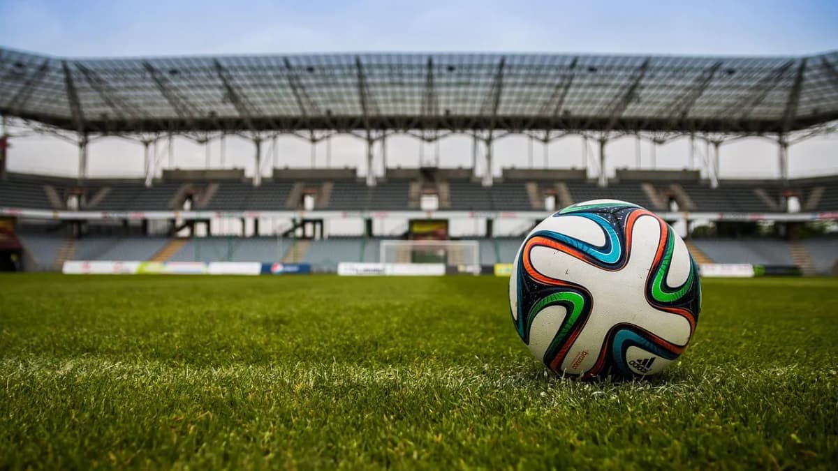 Football on the grass in front of an empty stadium