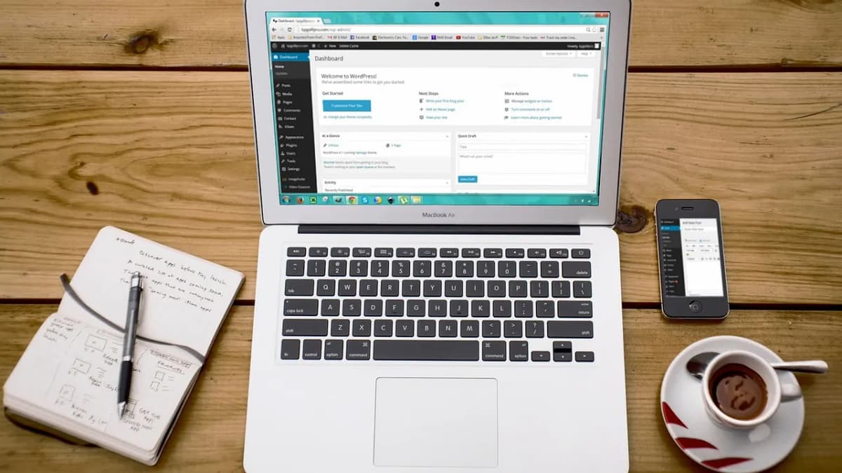 Laptop showing a website dashboard on a wooden desk with a notebook and coffee