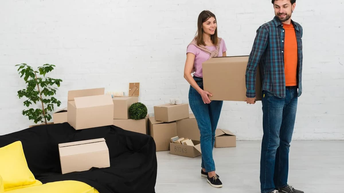 Couple carrying cardboard boxes while moving into a new home