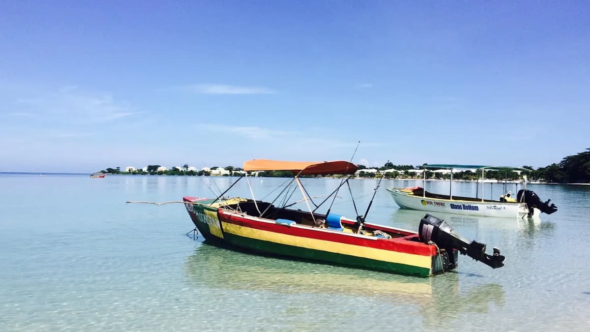 Colourful fishing boat in green, yellow and black on clear water off a Jamaican beach