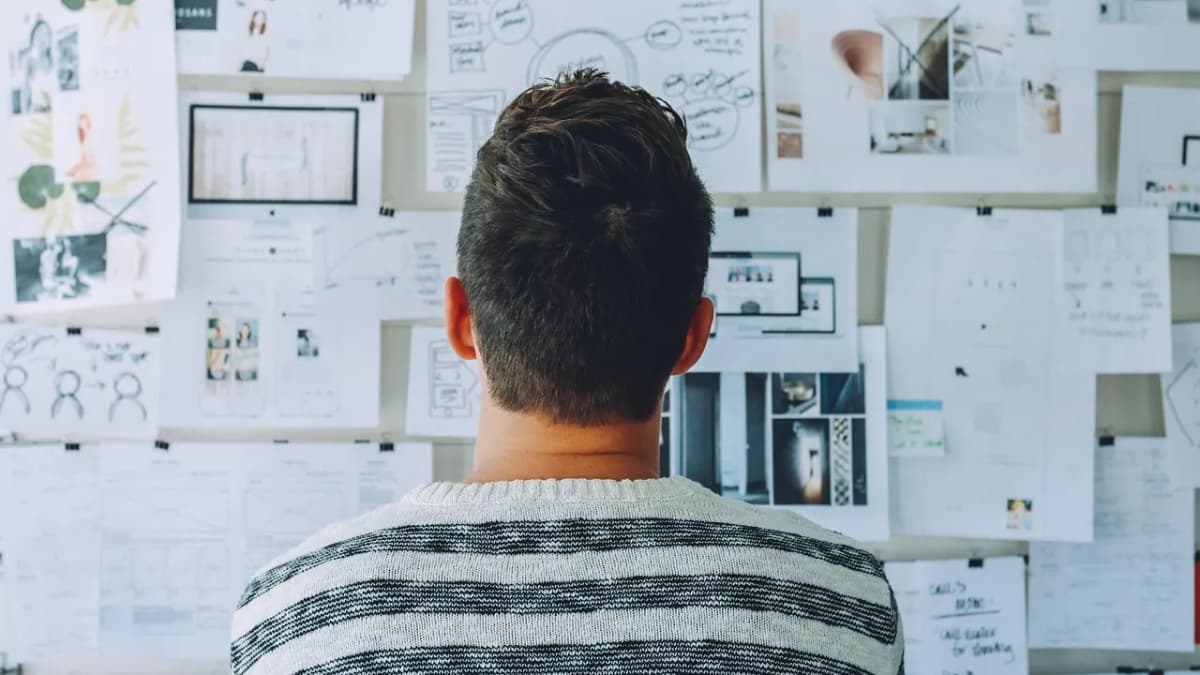 Man standing in front of a wall covered in sketches and planning notes